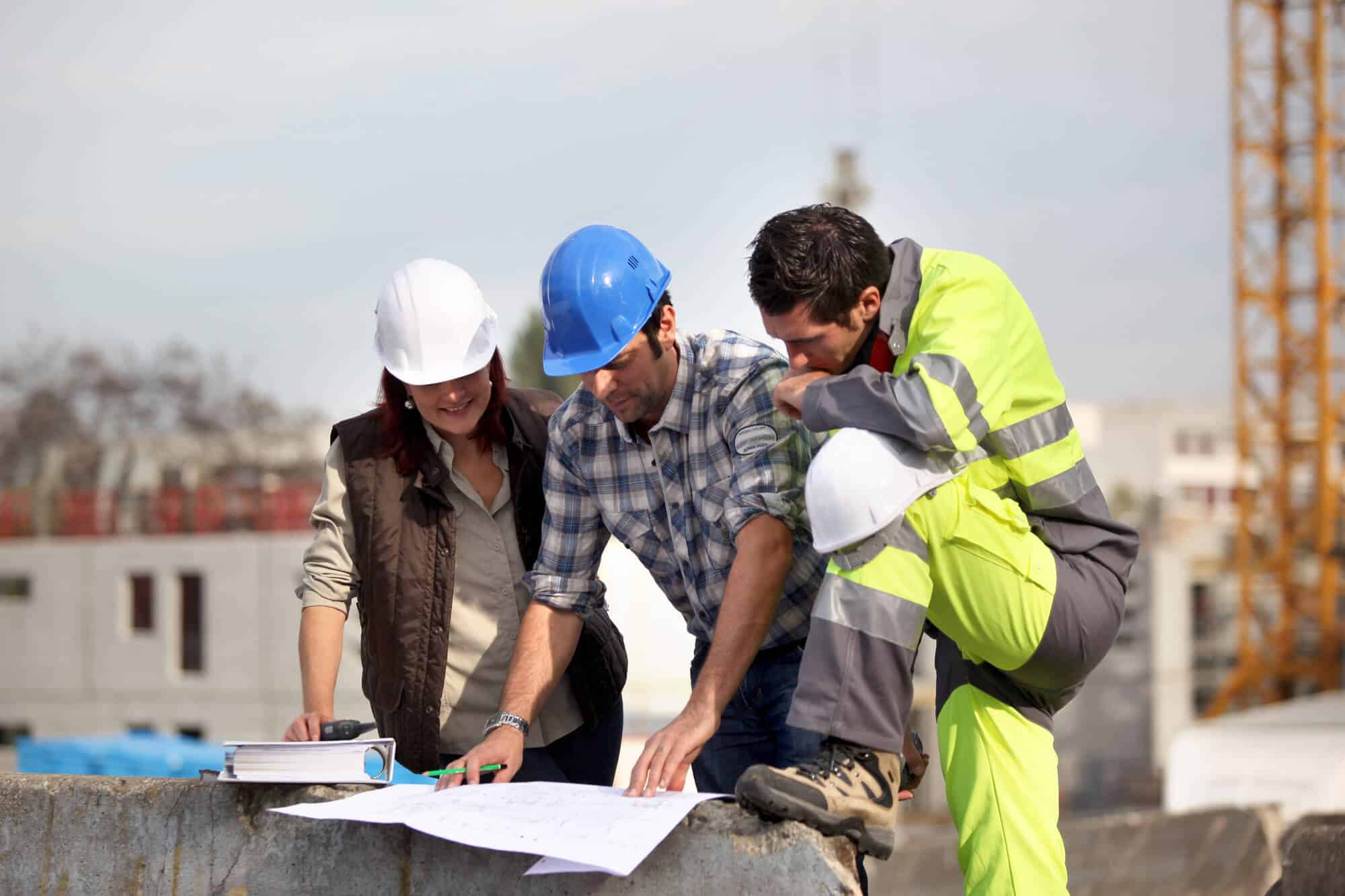 group of workers in a construction site looking at a site plan